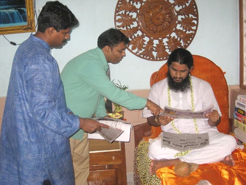 HJS's Shri. Ramesh Shinde showing News report about NCERT issue to HH Brahmeshanand Swami