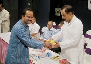 Dr. Swam receiving the holy book from Mr. Abhay Vartak, Sanatan Sanstha