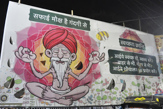 शौचालय के उपयोग हेतू एक साधु के चित्रवाला बनाया गया होर्डिंग