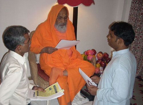 Pujya Swamiji reading printed pages of website