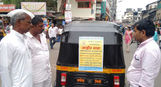 Residents reading the poster stuck on the back of an auto-rickshaw