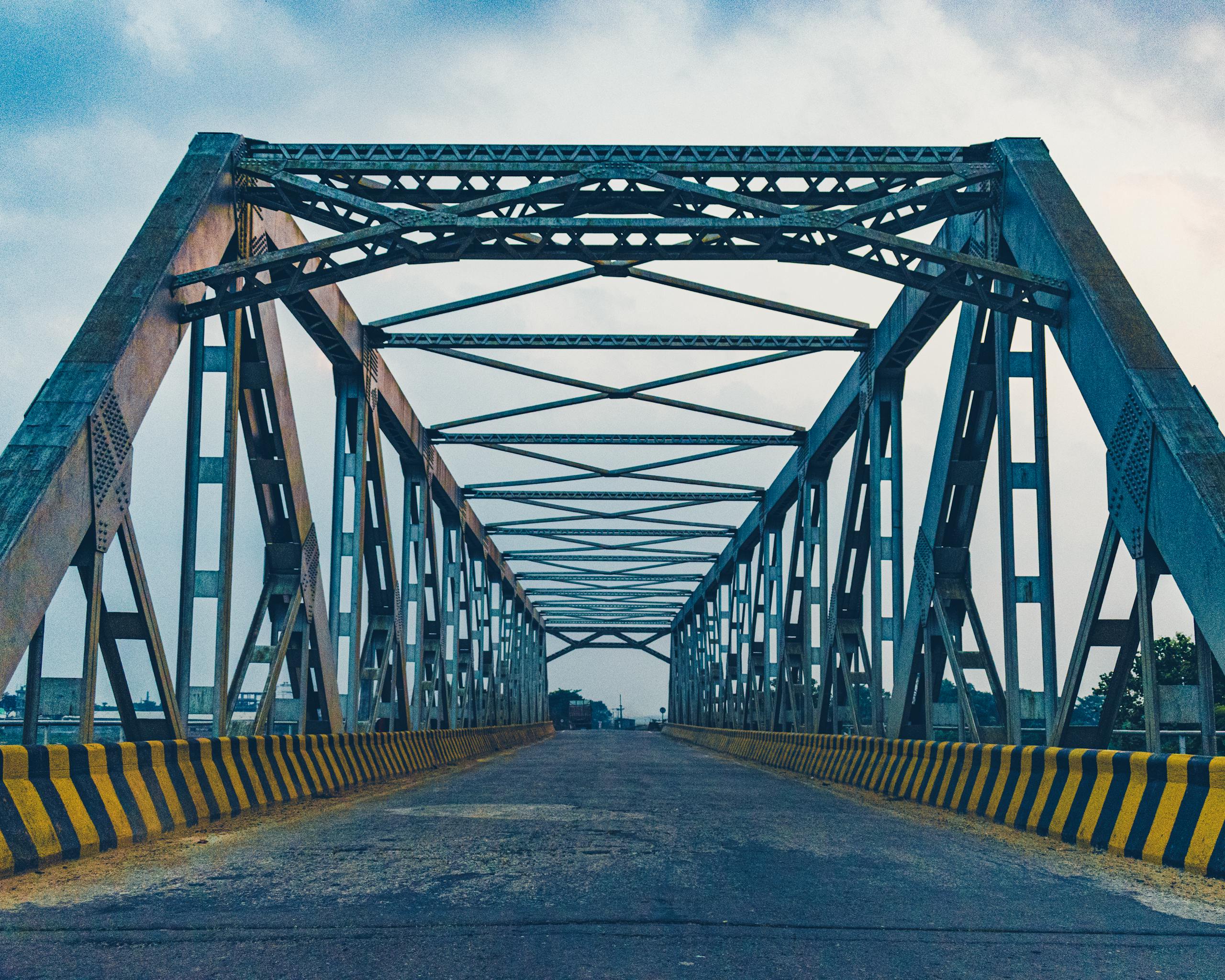 A perspective view of a symmetrical steel bridge with clear skies.